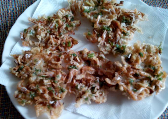 Fried crispy fritters with herbs on a white plate lined with a napkin, brown and green colors, casual homemade setting